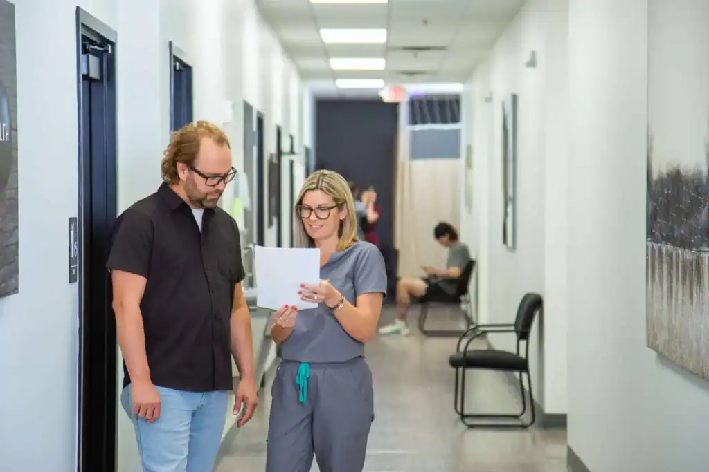 Nurse giving patient check-out papers after neck pain signs have been addressed